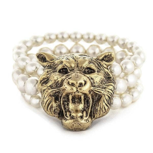 A three strand pearl bracelet with a 22K antique gold plated brass lion face centerpiece, hand crafted in New York.