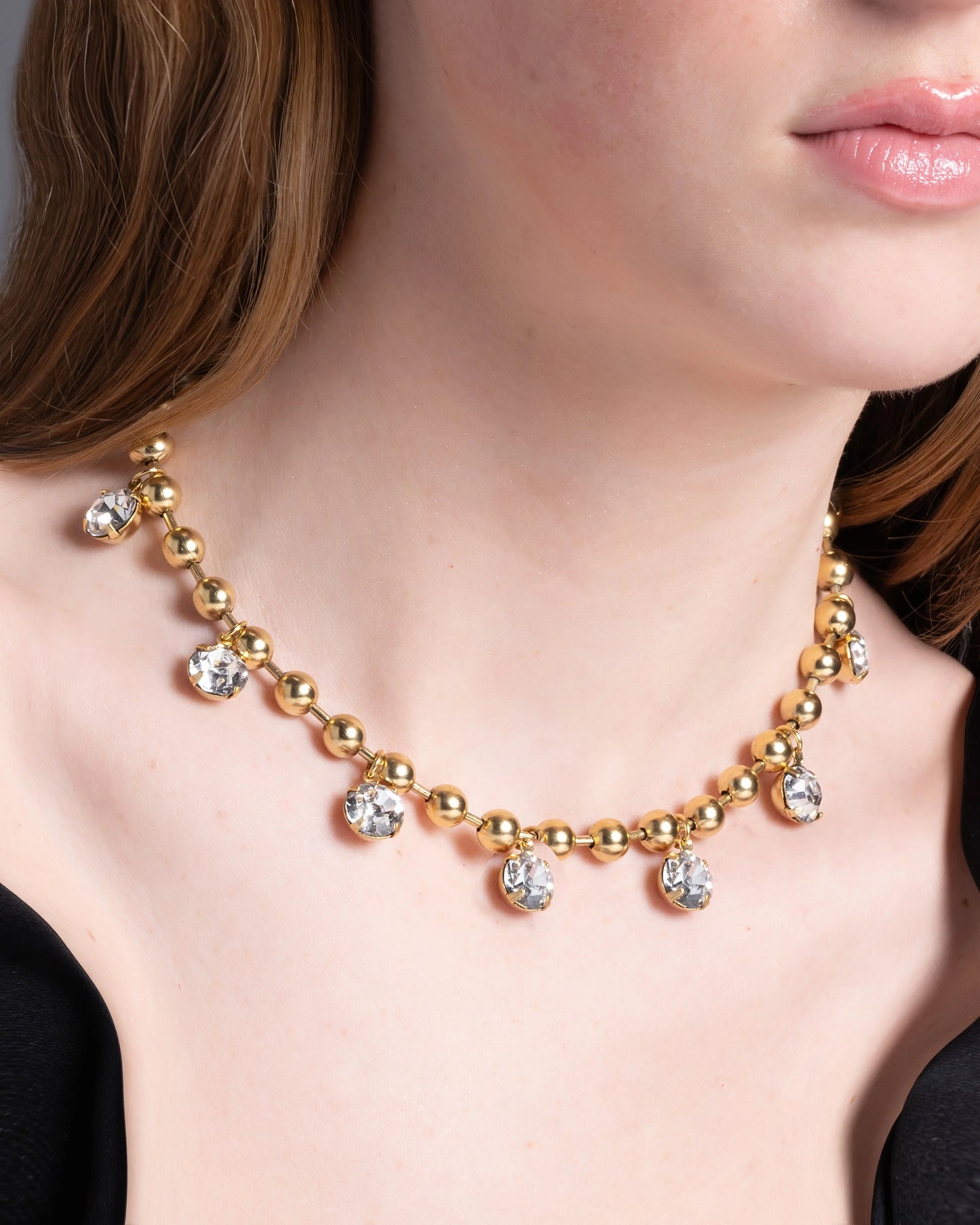 A close-up image of a woman's neck wearing a 22K gold plated over brass necklace with small diamond-like adornments.