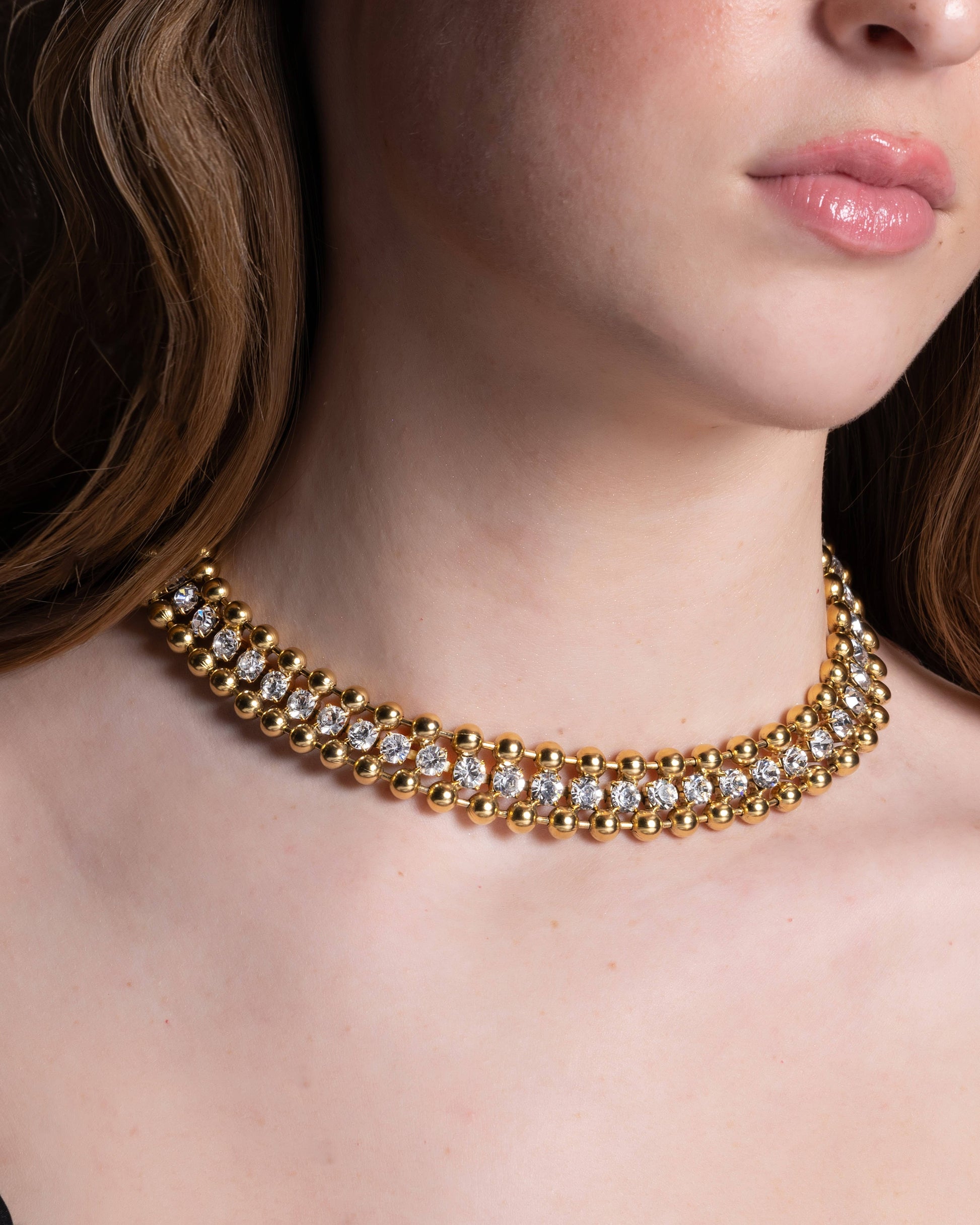 A close-up image of a woman's neck wearing a 22K gold plated over brass choker necklace with no visible brand marking.