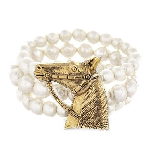 A bracelet with white pearls and a gold-colored horse head embellishment, hand crafted in New York.