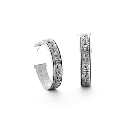 Pair of silver hoop earrings with intricate designs on a white background