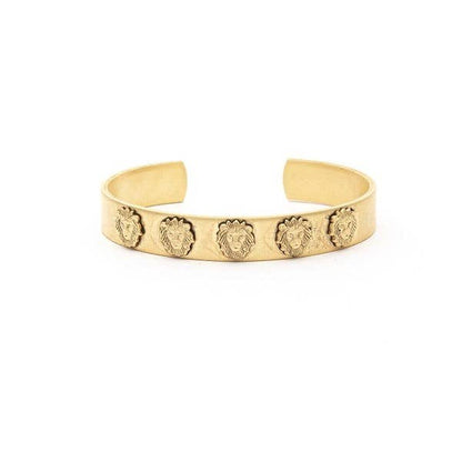 A gold-colored cuff bracelet featuring a series of mini lion heads as part of its design, displayed against a white background.