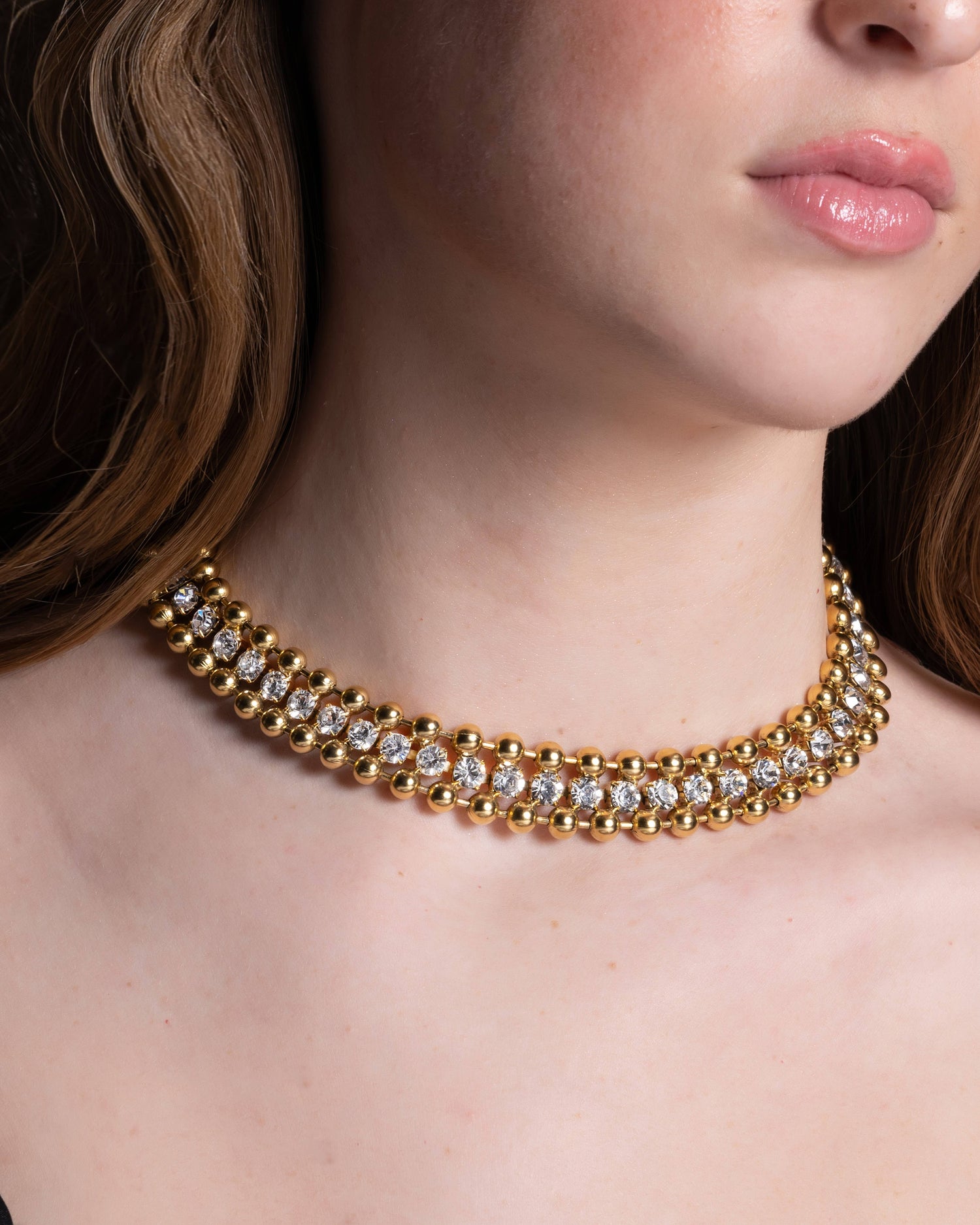 A close-up image of a woman's neck wearing a 22K gold plated over brass choker necklace with no visible brand marking.