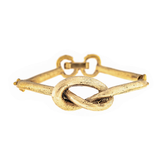 Gold bracelet with a knot design on a white background