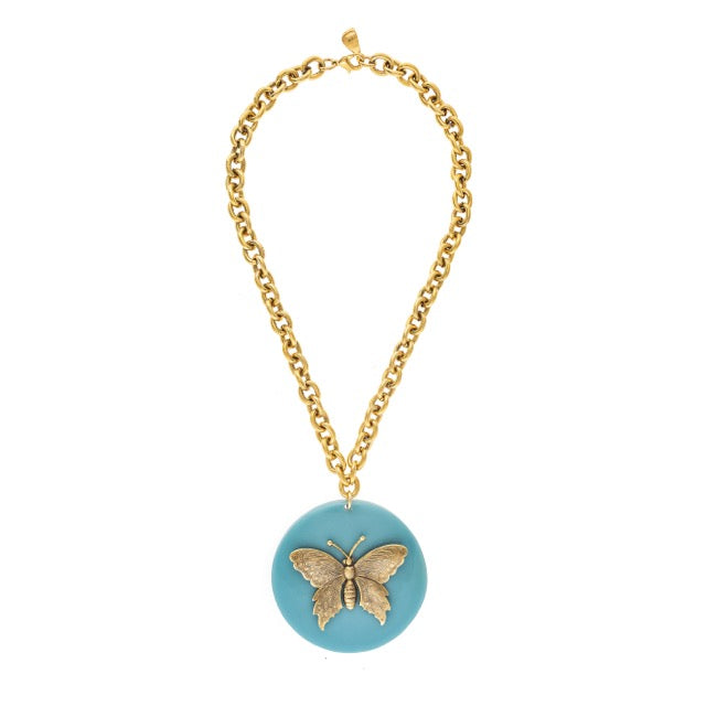 Gold chain necklace with a blue pendant featuring a butterfly design on a white background