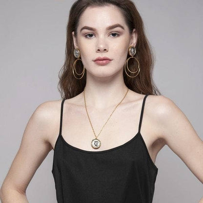 A woman wearing a black tank top with a vintage two-tone gold-plated necklace and matching earrings.